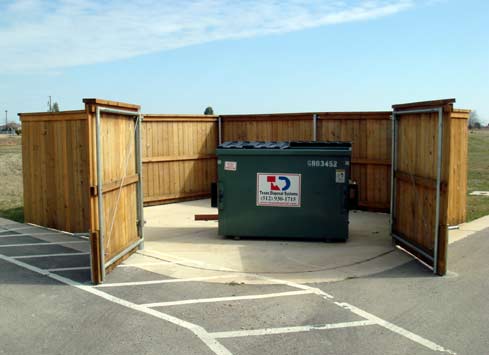 wood privacy fence around garbage dumpsters gate open
